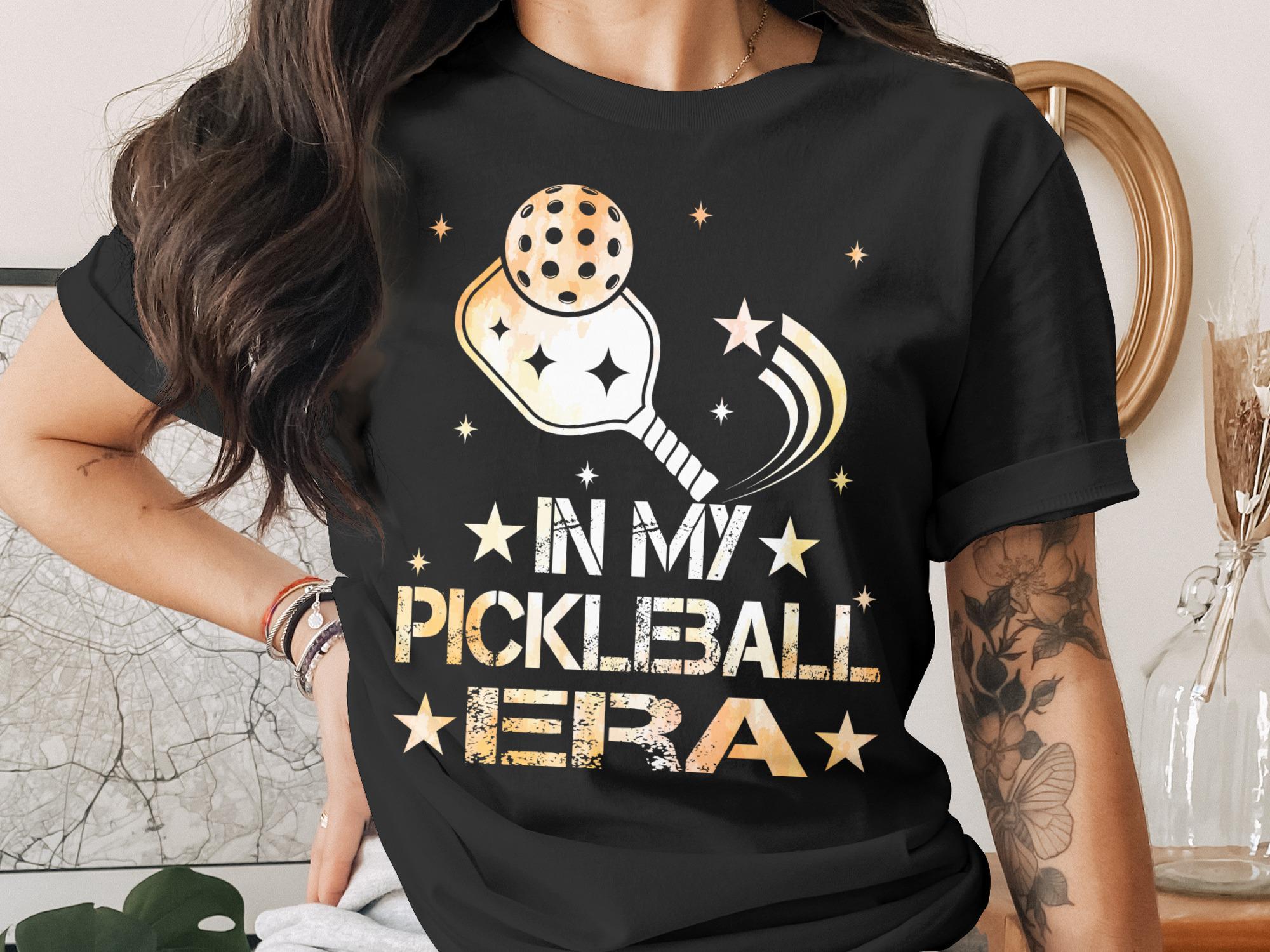 Black t-shirt with "In My Pickleball Era" text and pickleball graphics.