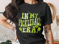 Black t-shirt with "In My Pickleball Era" text and pickleball graphics.
