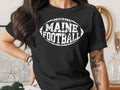Black t-shirt with "Maine Football" text in a football shape.