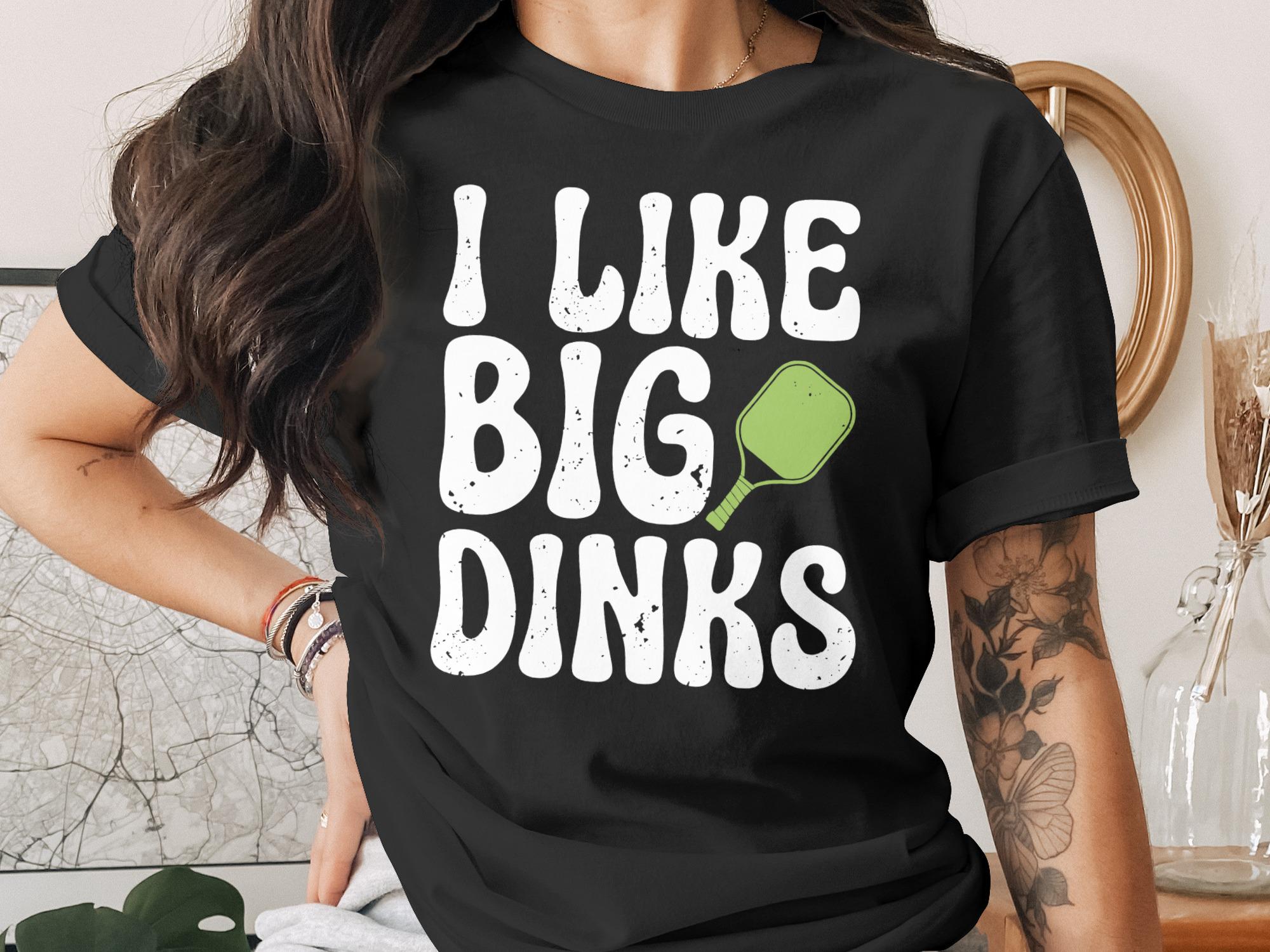 Black t-shirt with white text "I LIKE BIG DINKS" and a green pickleball paddle.