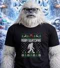 Yeti wearing a Merry Squatchmas ugly sweater with a Bigfoot silhouette.