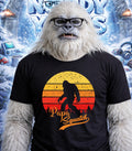 Yeti wearing glasses and a "Papa Squatch" t-shirt against a snowy background.