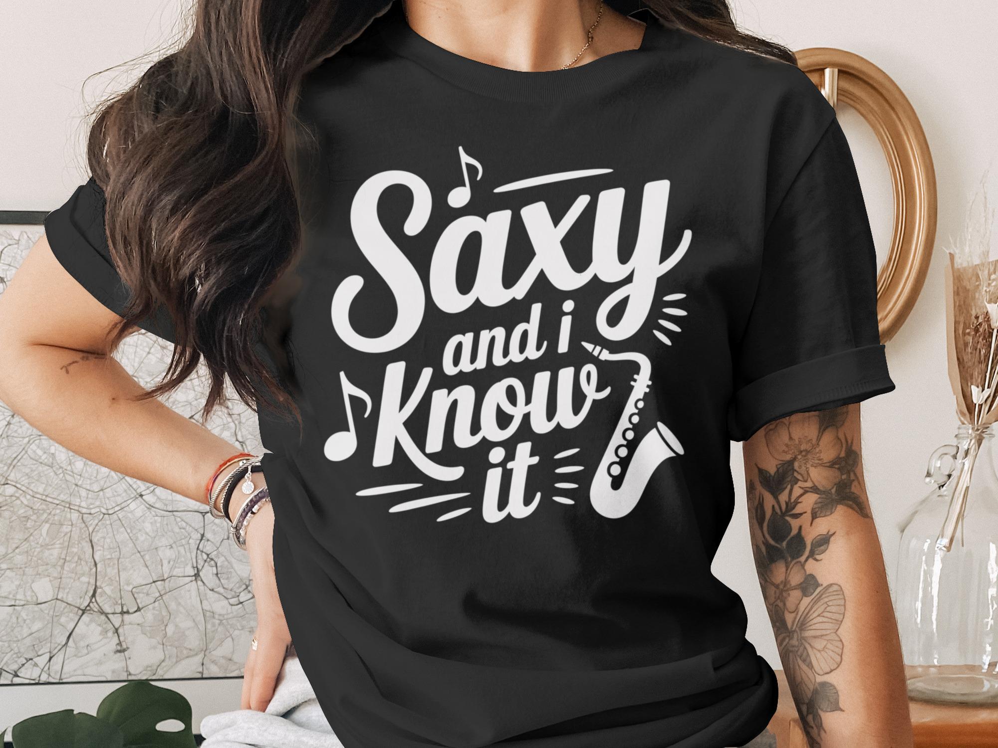 Black t-shirt with "Saxy and I Know It" and saxophone graphic.