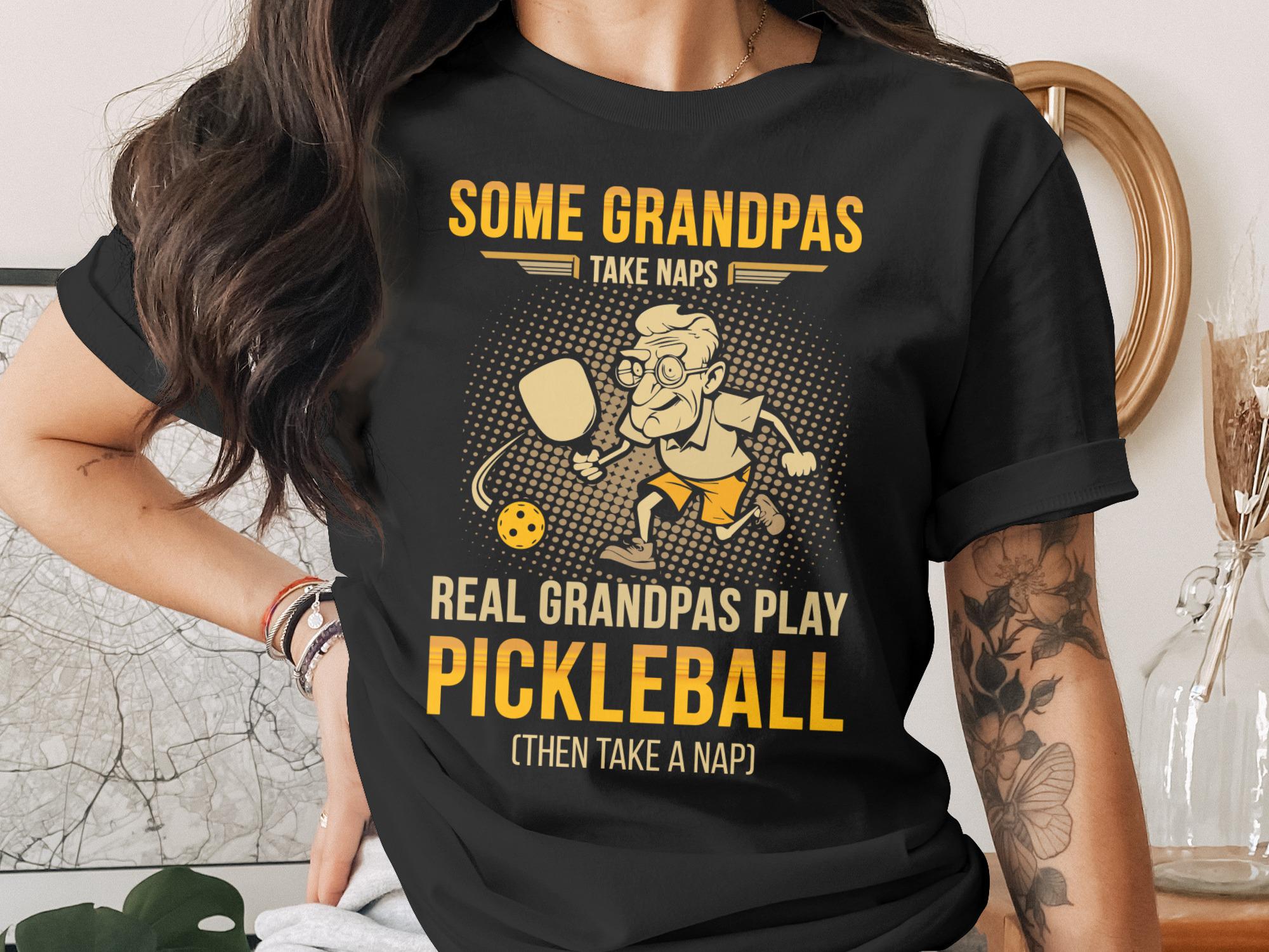 T-shirt with cartoon grandpa playing pickleball and text "Some Grandpas Take Naps. Real Grandpas Play Pickleball (Then Take a Nap)."
