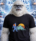 Yeti wearing glasses and a t-shirt with a Colorado mountain sunset graphic.