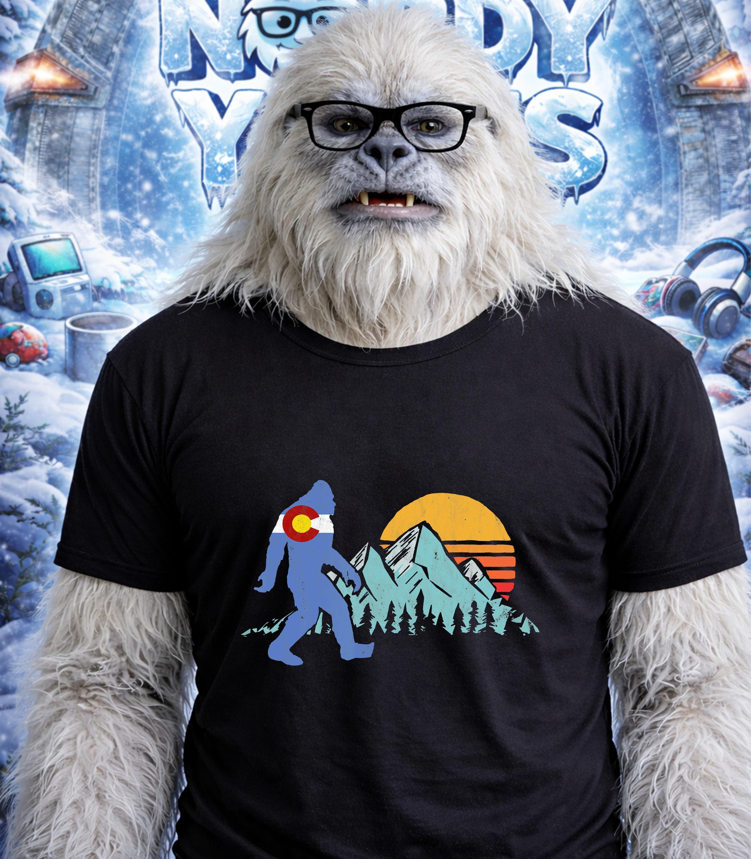 Yeti wearing glasses and a t-shirt with a Colorado mountain sunset graphic.