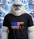 Yeti wearing glasses and a t-shirt with a distressed American flag and Bigfoot silhouette.