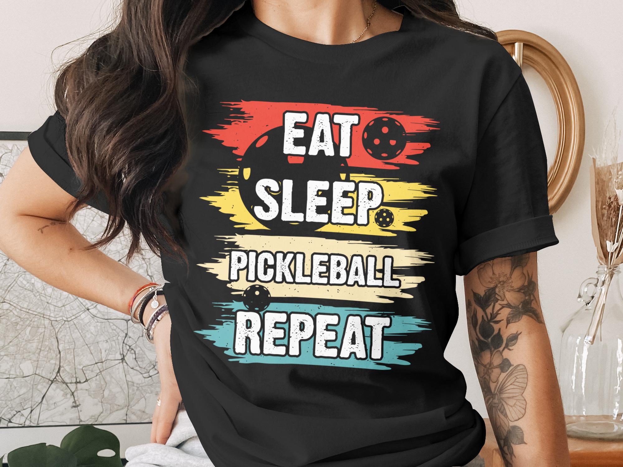 Black t-shirt with "Eat Sleep Pickleball Repeat" in colorful text.