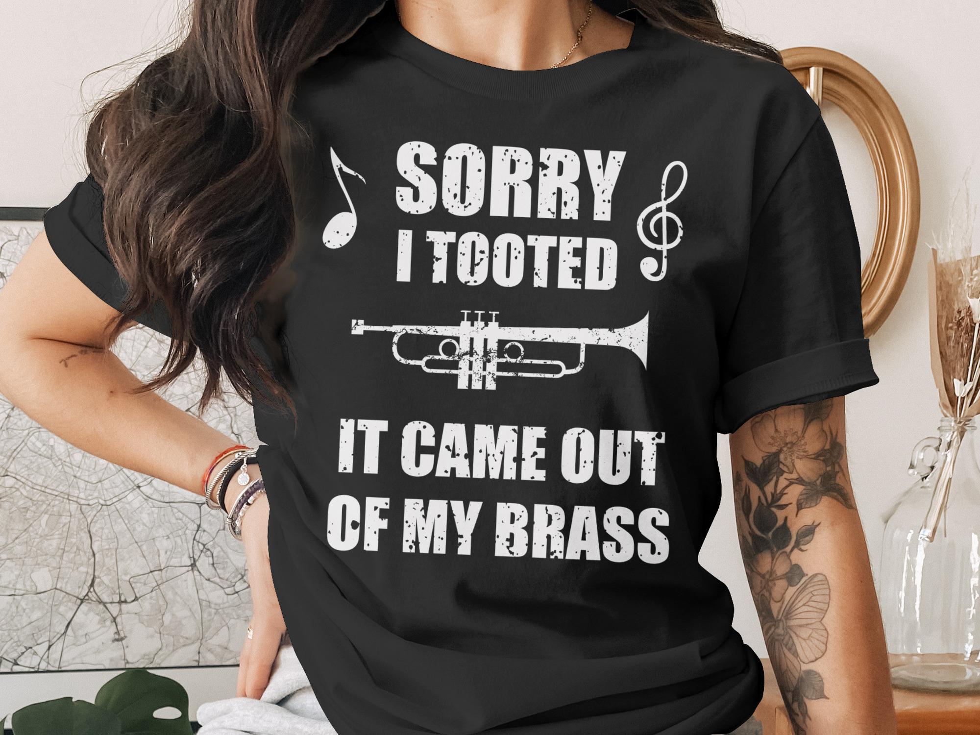 Black t-shirt with "Sorry I Tooted It Came Out of My Brass" and trumpet graphic.