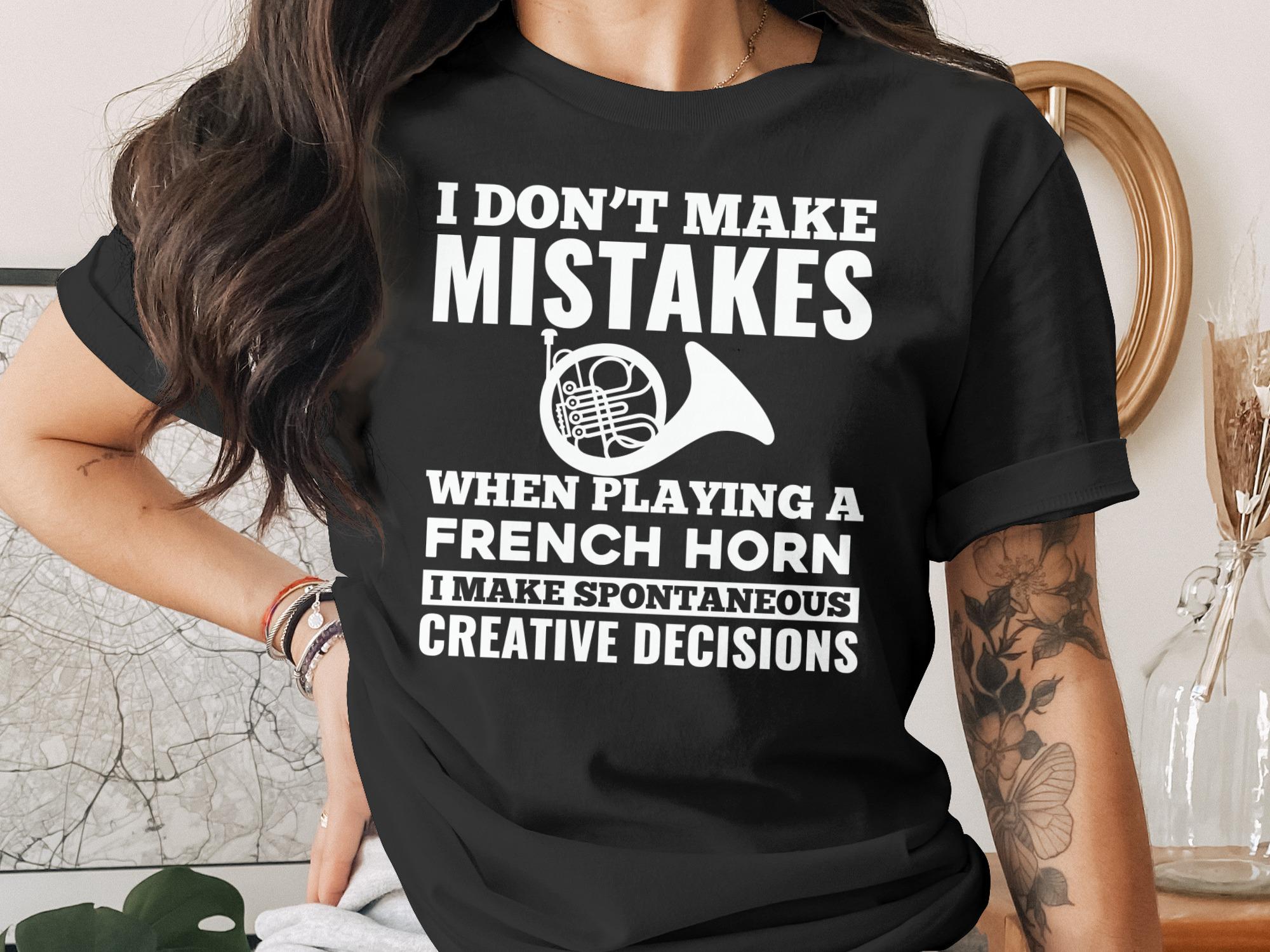 Black t-shirt with "I Don't Make Mistakes When Playing a French Horn, I Make Spontaneous Creative Decisions" and a French horn graphic.