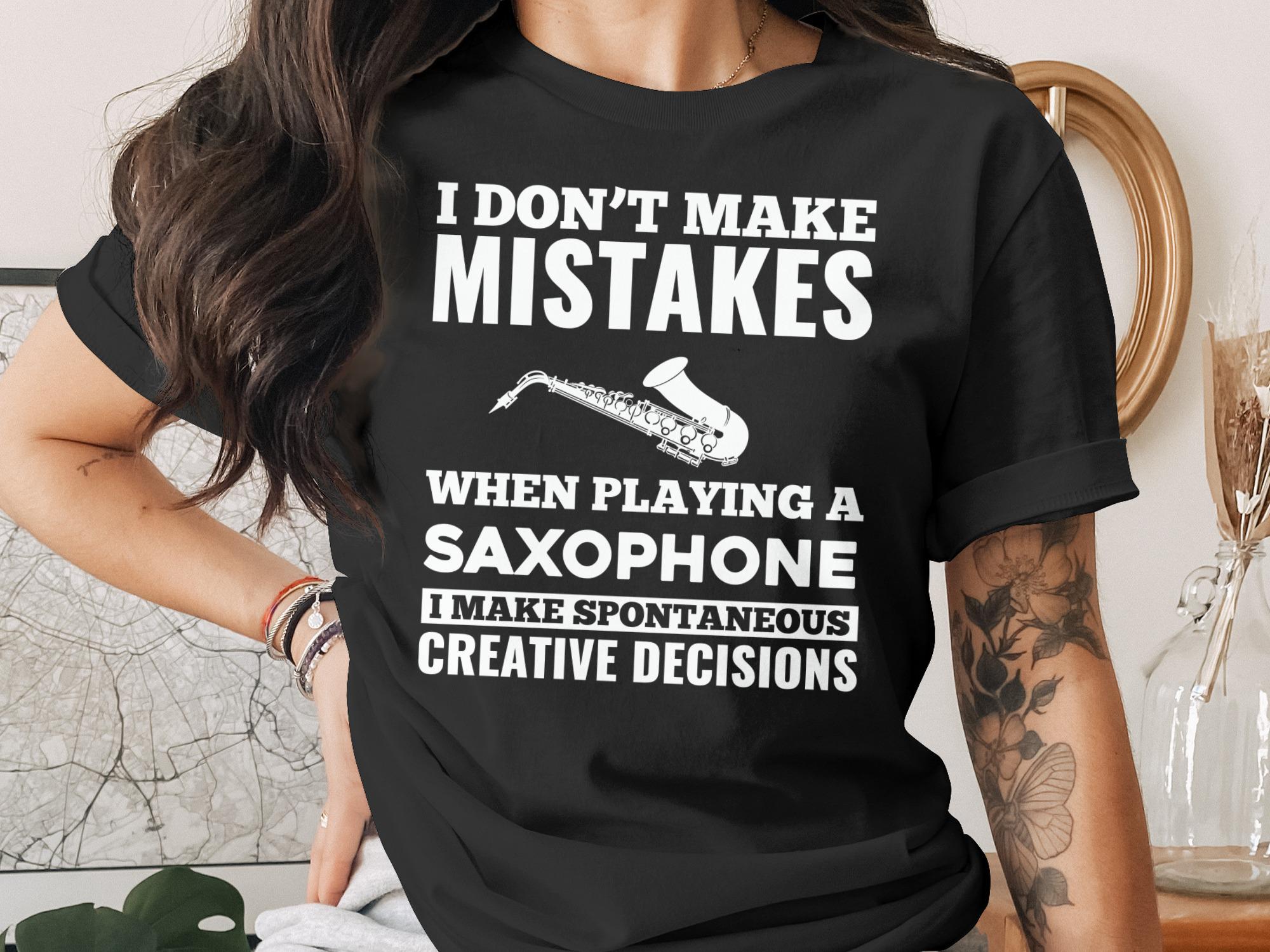 Black t-shirt with white text and saxophone graphic reading "I Don't Make Mistakes When Playing A Saxophone I Make Spontaneous Creative Decisions."